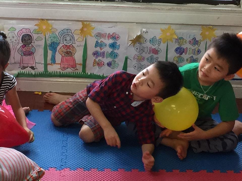 Two children playing with a yellow balloon on a mat