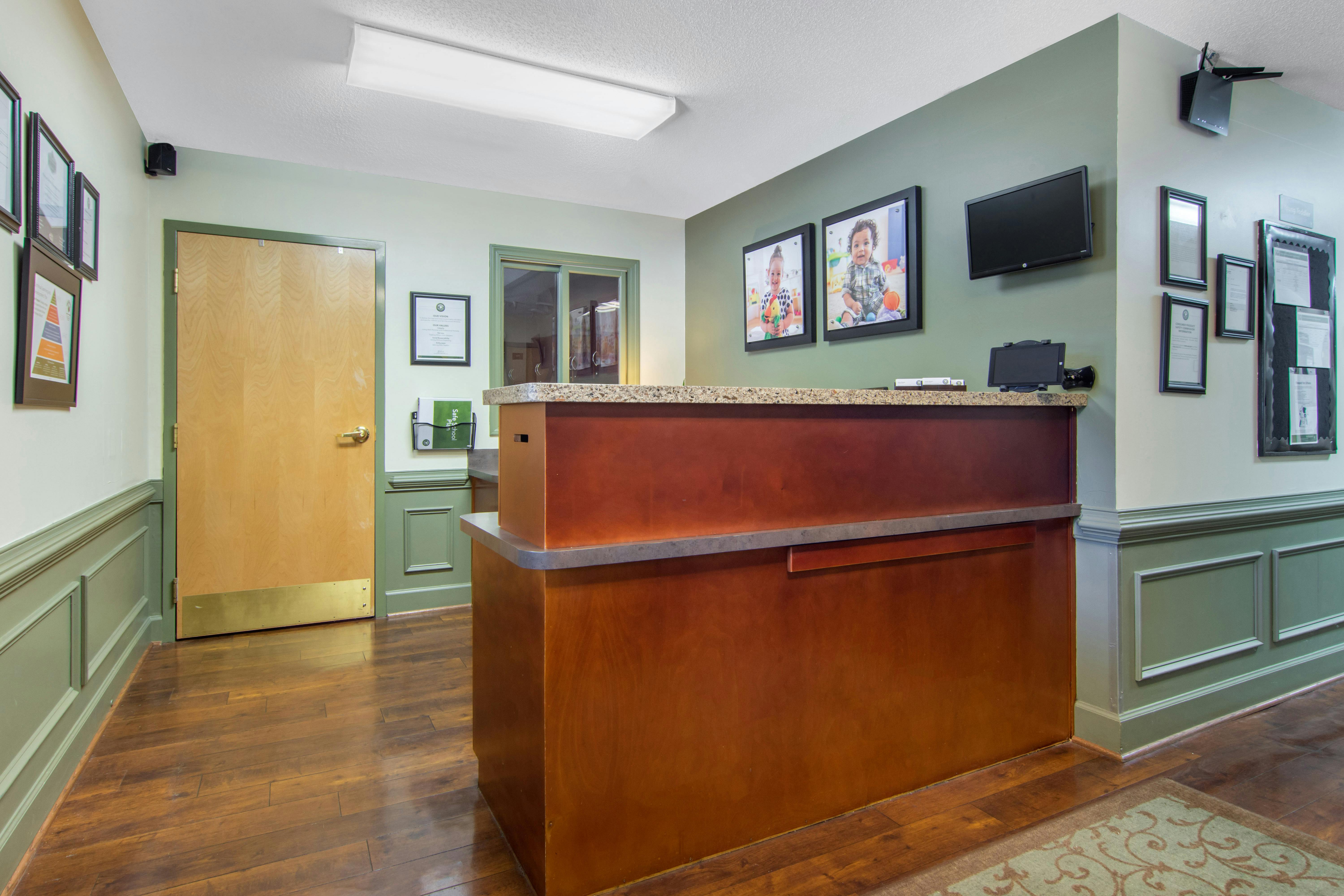 Reception area with a wooden desk and two framed photos of children