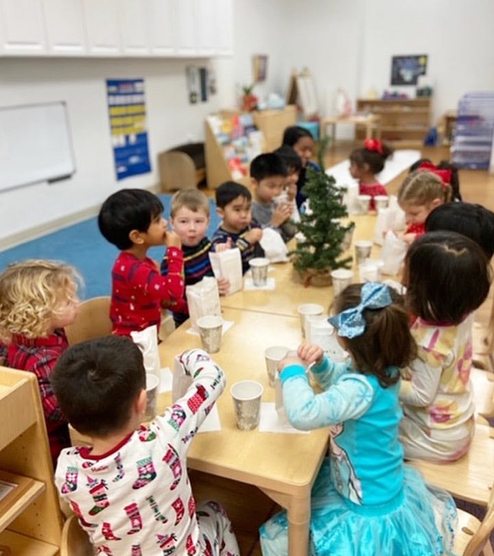 Children sitting at a table with cups and a small Christmas tree