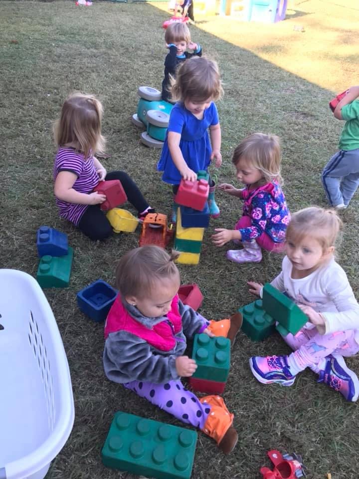 Children playing with large building blocks on grass