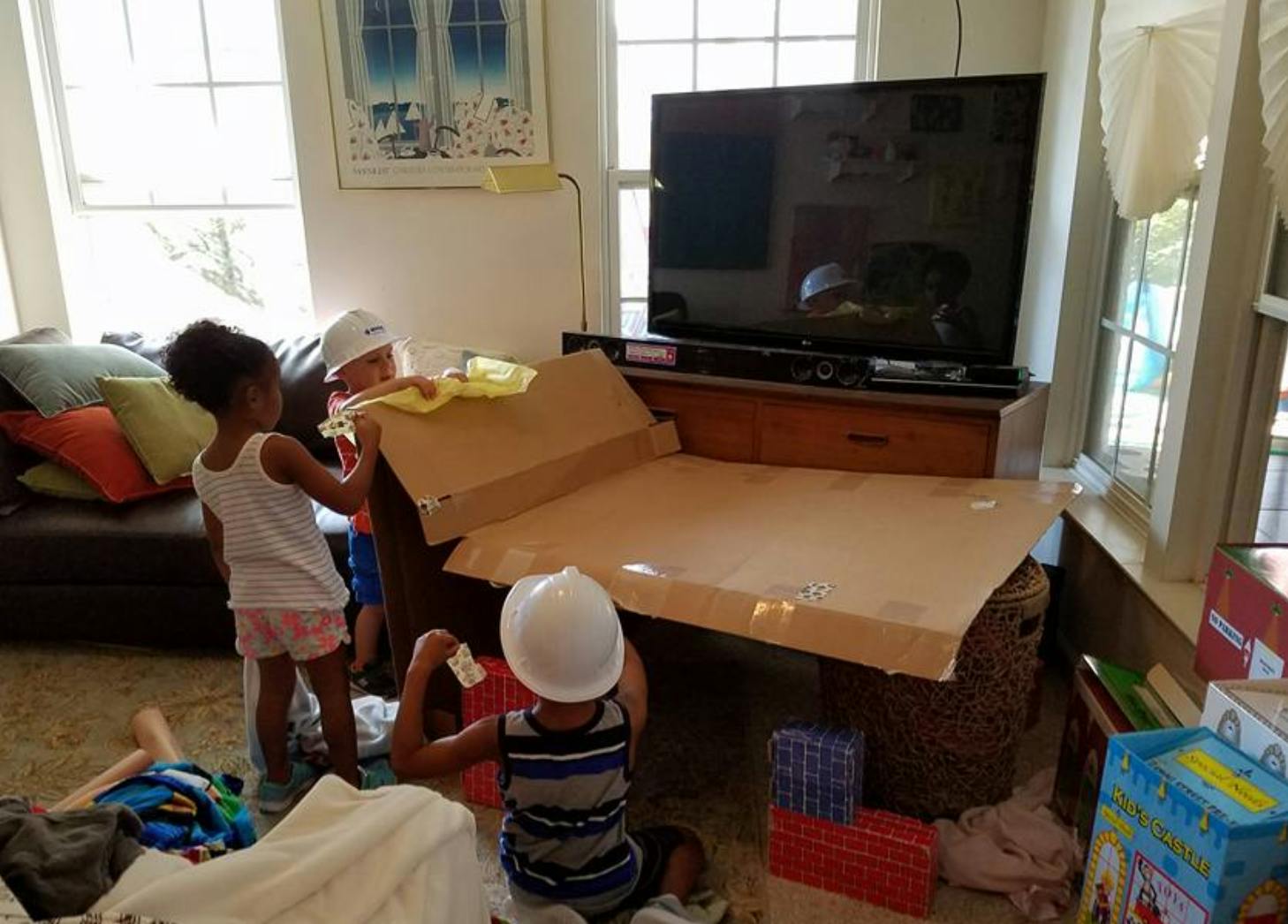 Children playing with cardboard boxes in a living room