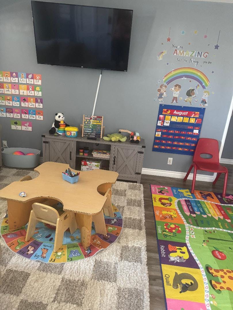 Children's play area with a small table and chairs, colorful rugs, and wall decorations