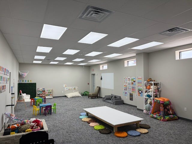 A large classroom with multiple play areas and child-sized tables