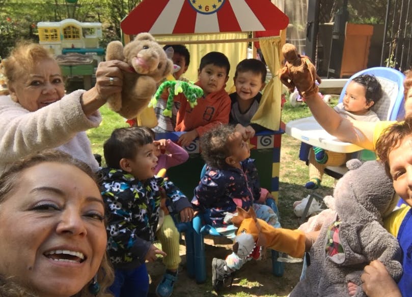 Adults and children holding up puppets and stuffed animals
