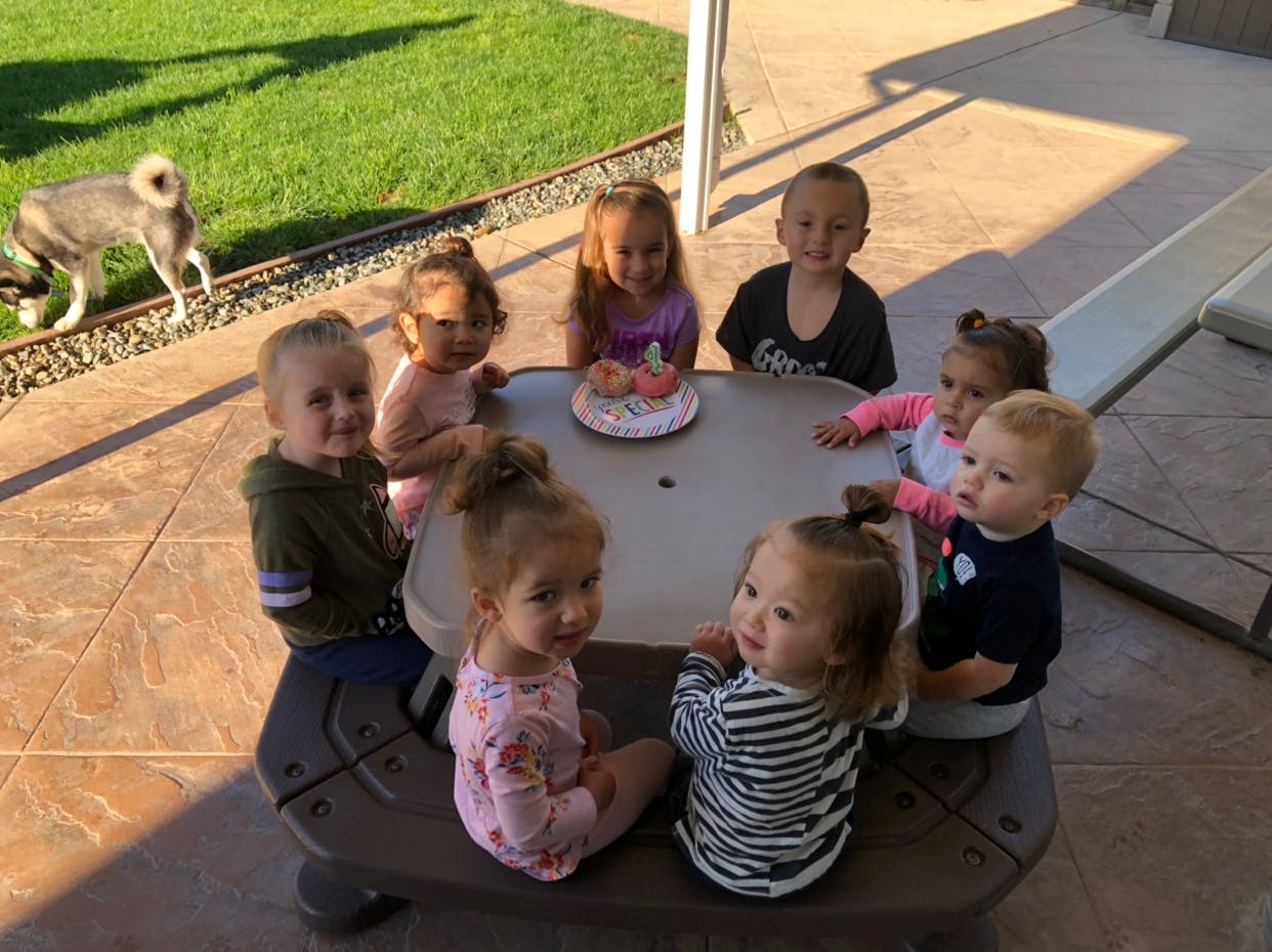 Seven children sitting around a table with a cake
