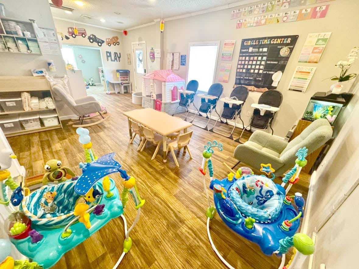 childcare room with baby jumpers, high chairs, and a play area