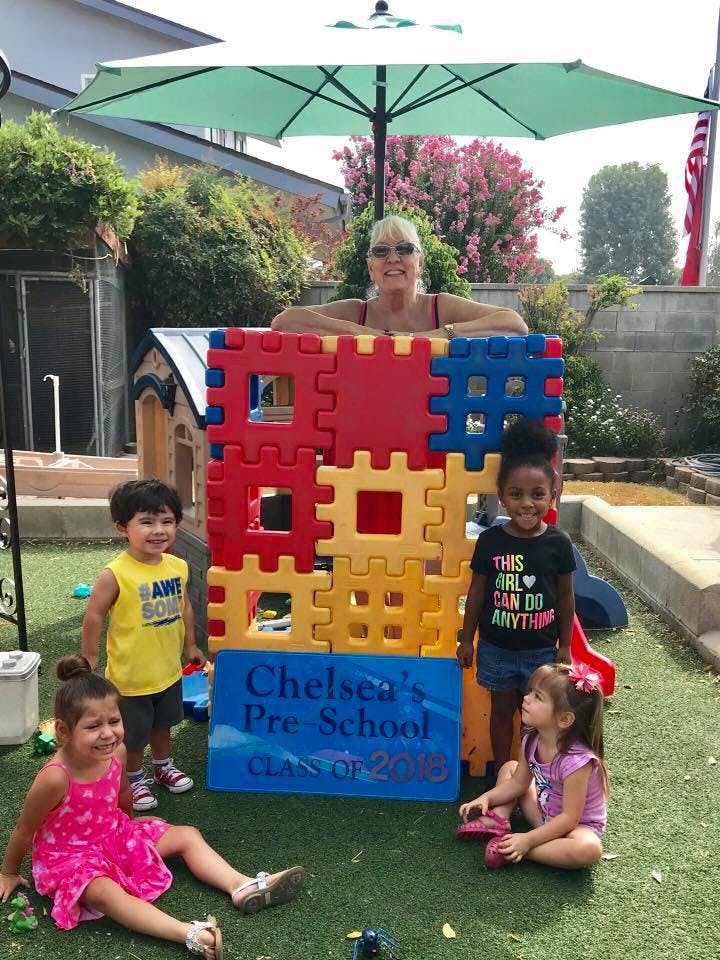 Adult and children with a large block structure and a sign for Chelsea's Pre-School