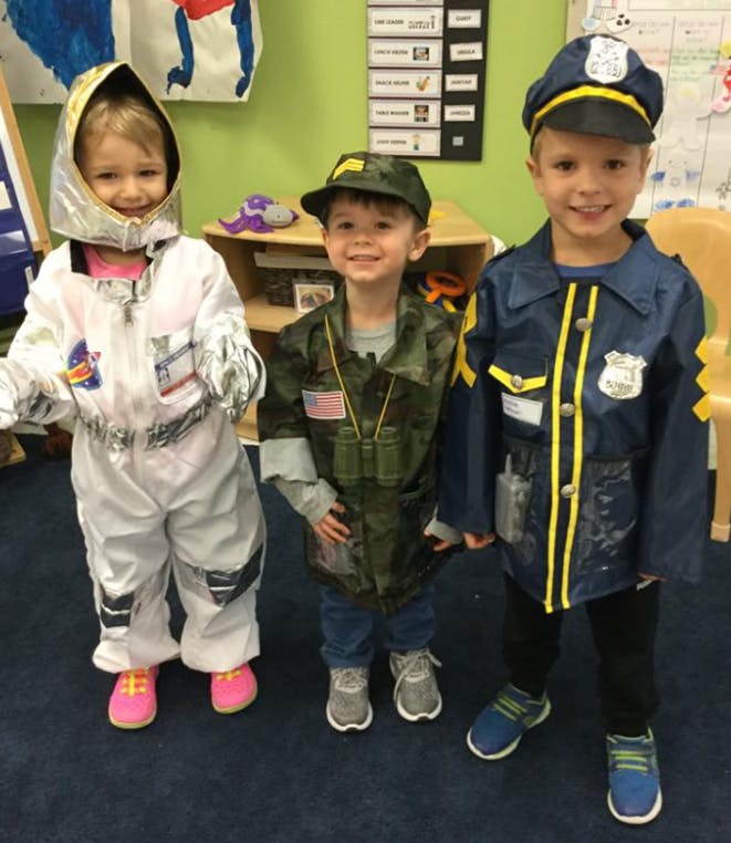 Three children in costumes, one as an astronaut, one as a soldier, one as a police officer