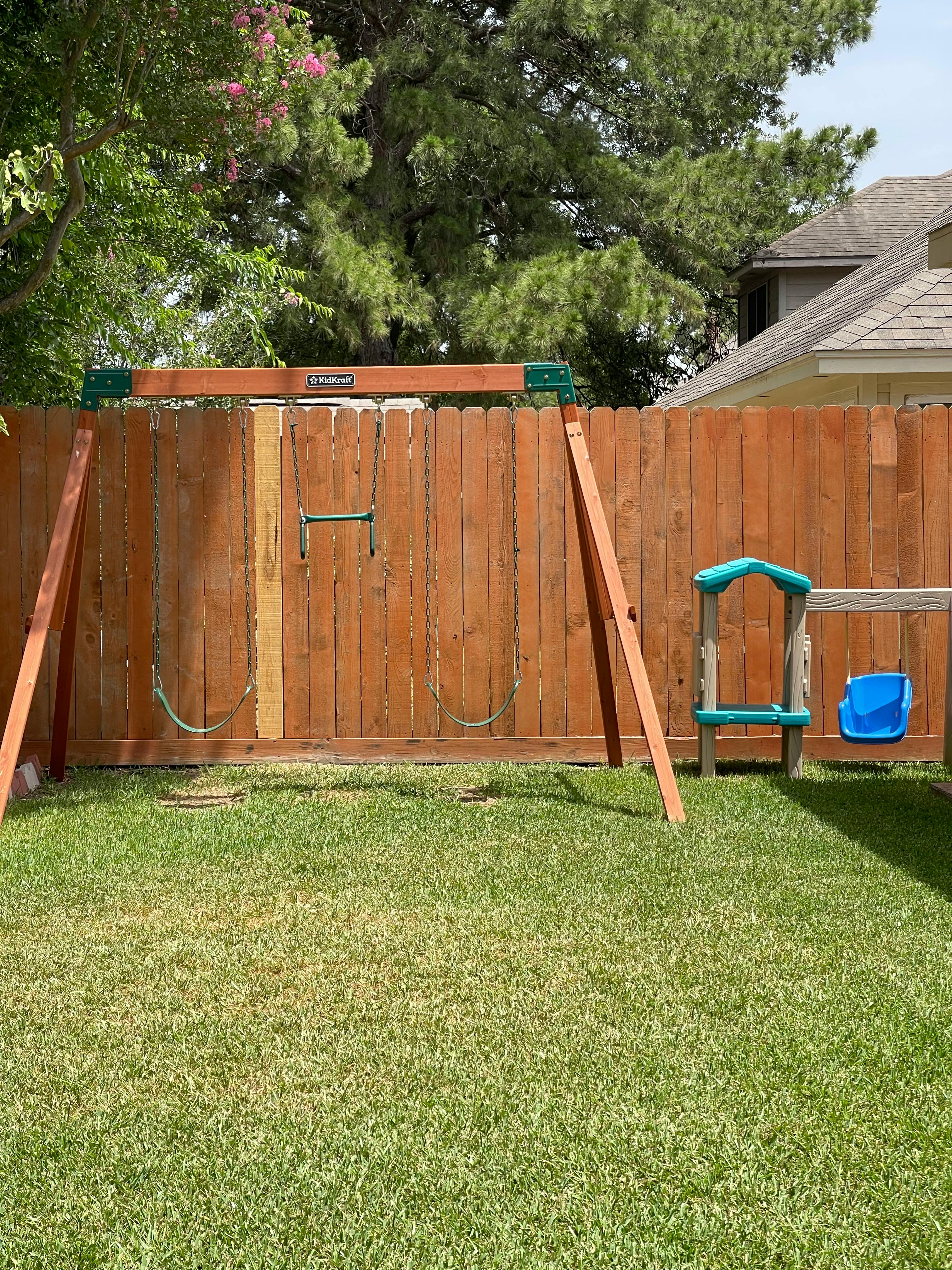 Swing set with two swings and a baby swing in a backyard