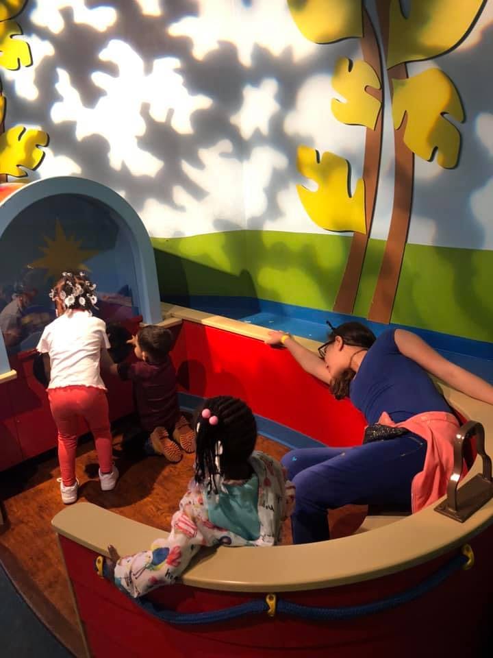 Children and an adult playing in a boat-shaped structure