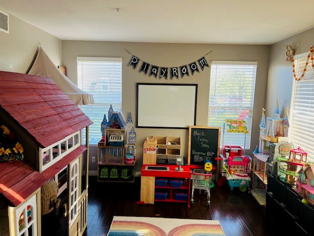 Playroom with a playhouse, toy kitchen, and banner that says "PLAYROOM"