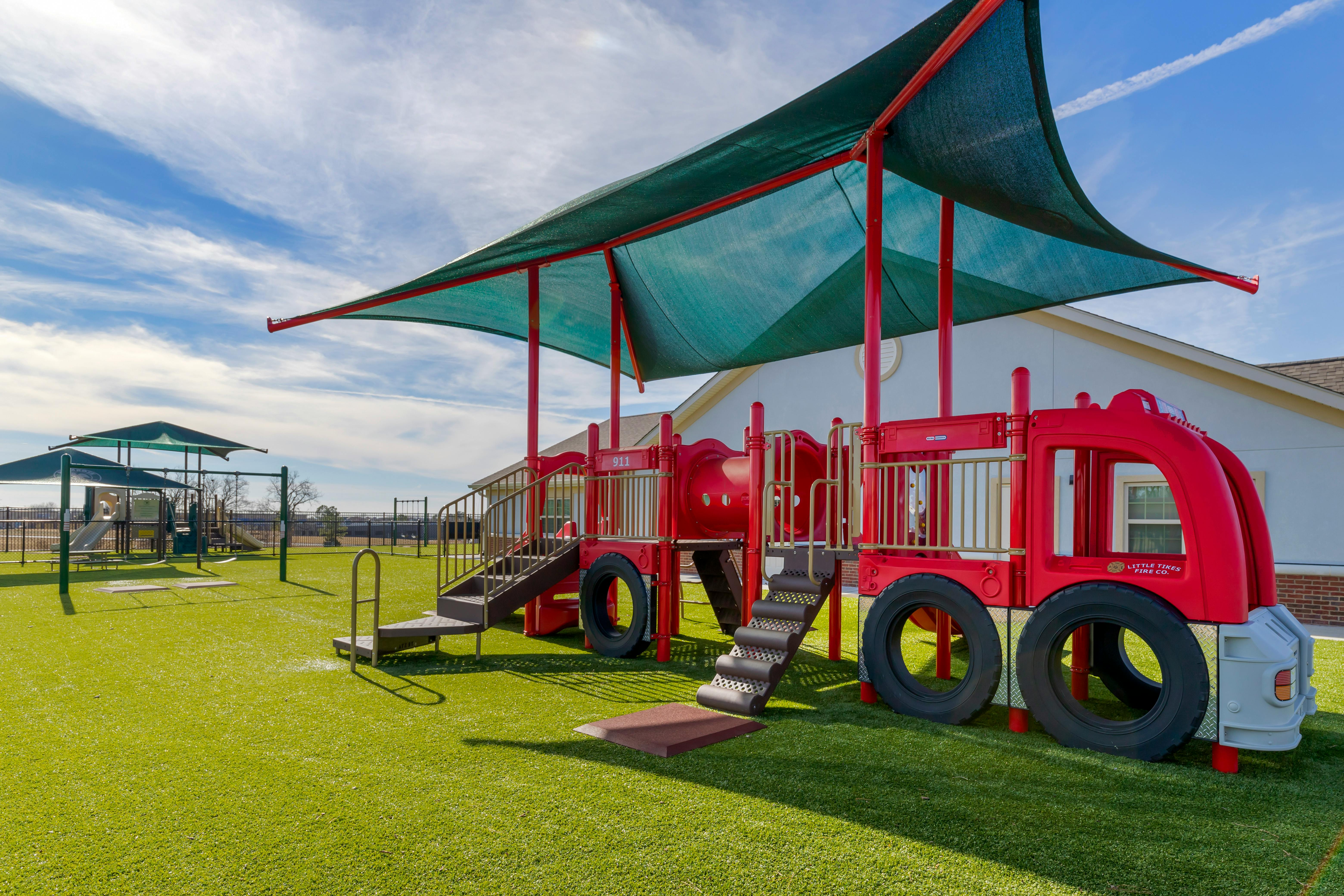 Red fire truck-themed playground equipment on green turf