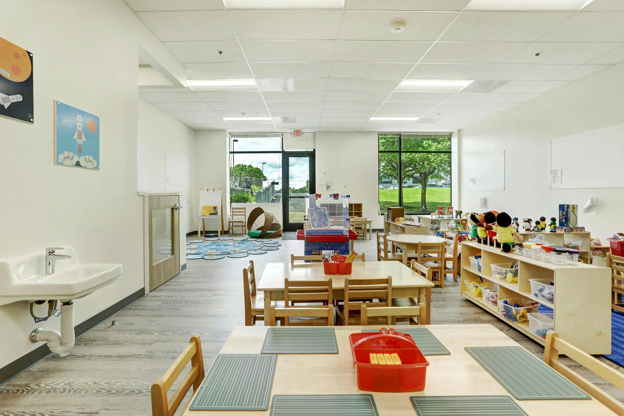 Classroom with child-sized tables and chairs, shelves of toys, and a sink