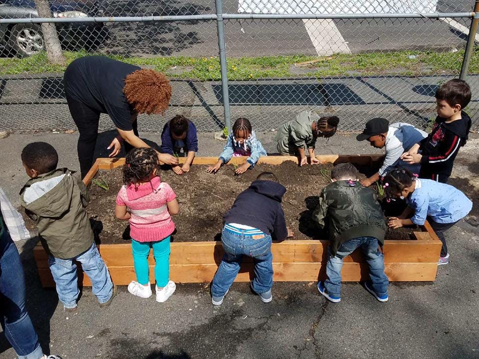 Adult and children digging in a raised garden bed