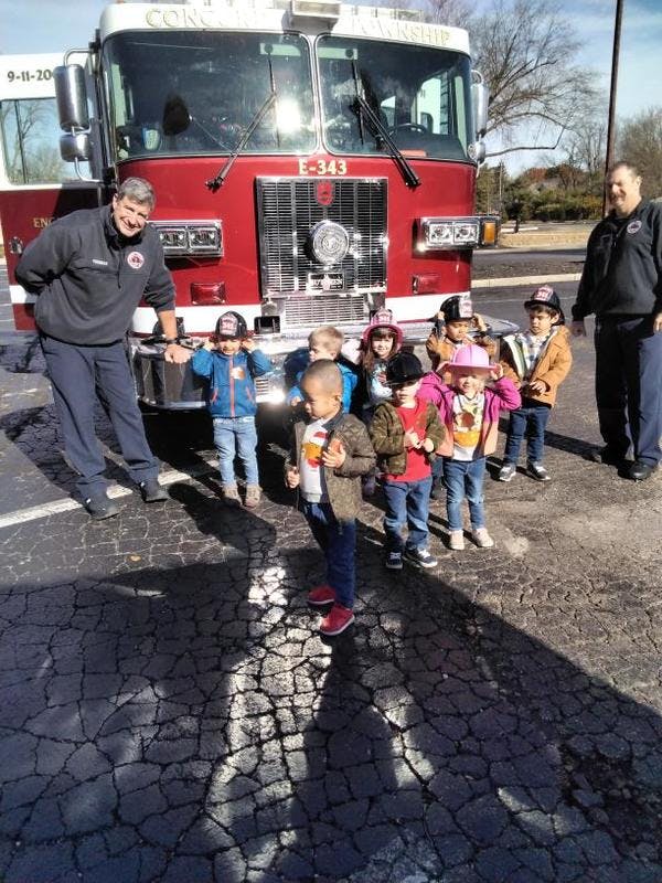 Two people and several children standing in front of a fire truck