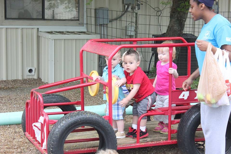Adult and three children playing in a red toy car