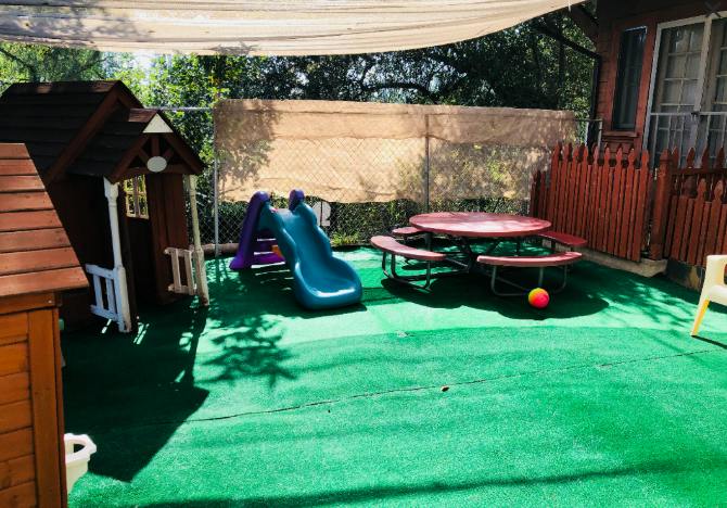 Playground with a playhouse, slide, picnic table, and ball
