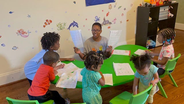 Person and children sitting around a table in a classroom