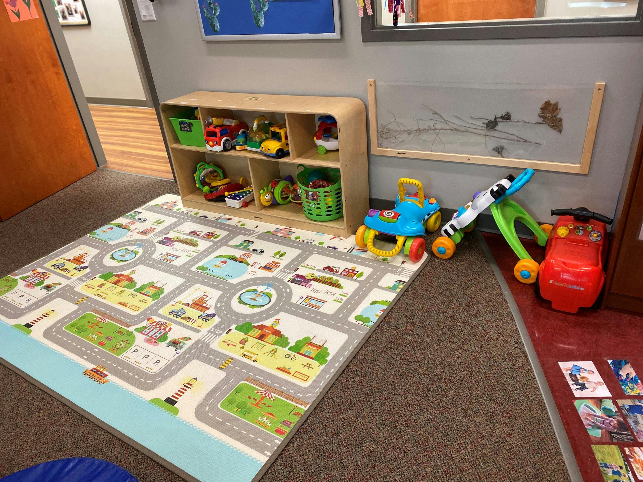 Playroom with a road map playmat, toy shelf, and various toys