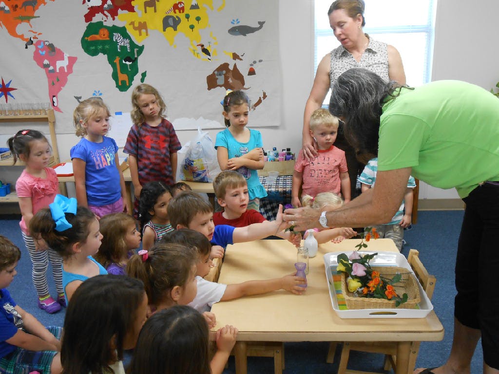 Adult showing children an activity at a table in a classroom