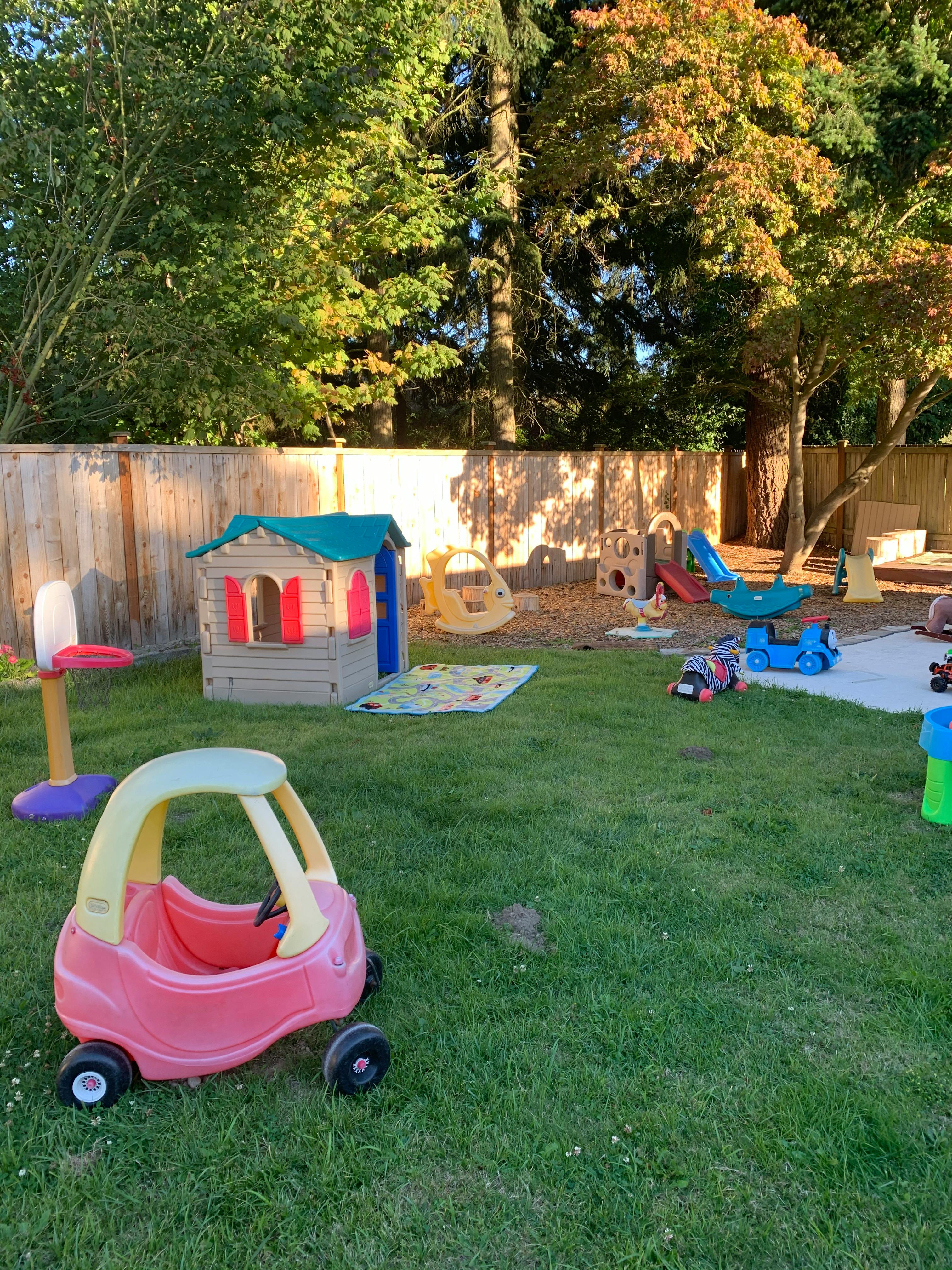 Outdoor play area with a toy car, playhouse, and other play equipment