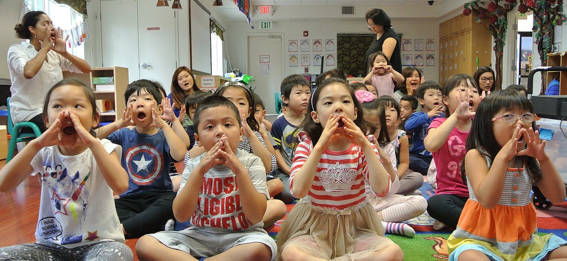Children sitting on the floor with hands cupped around their mouths