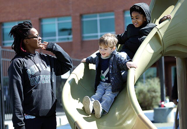Person watching two children on a playground slide