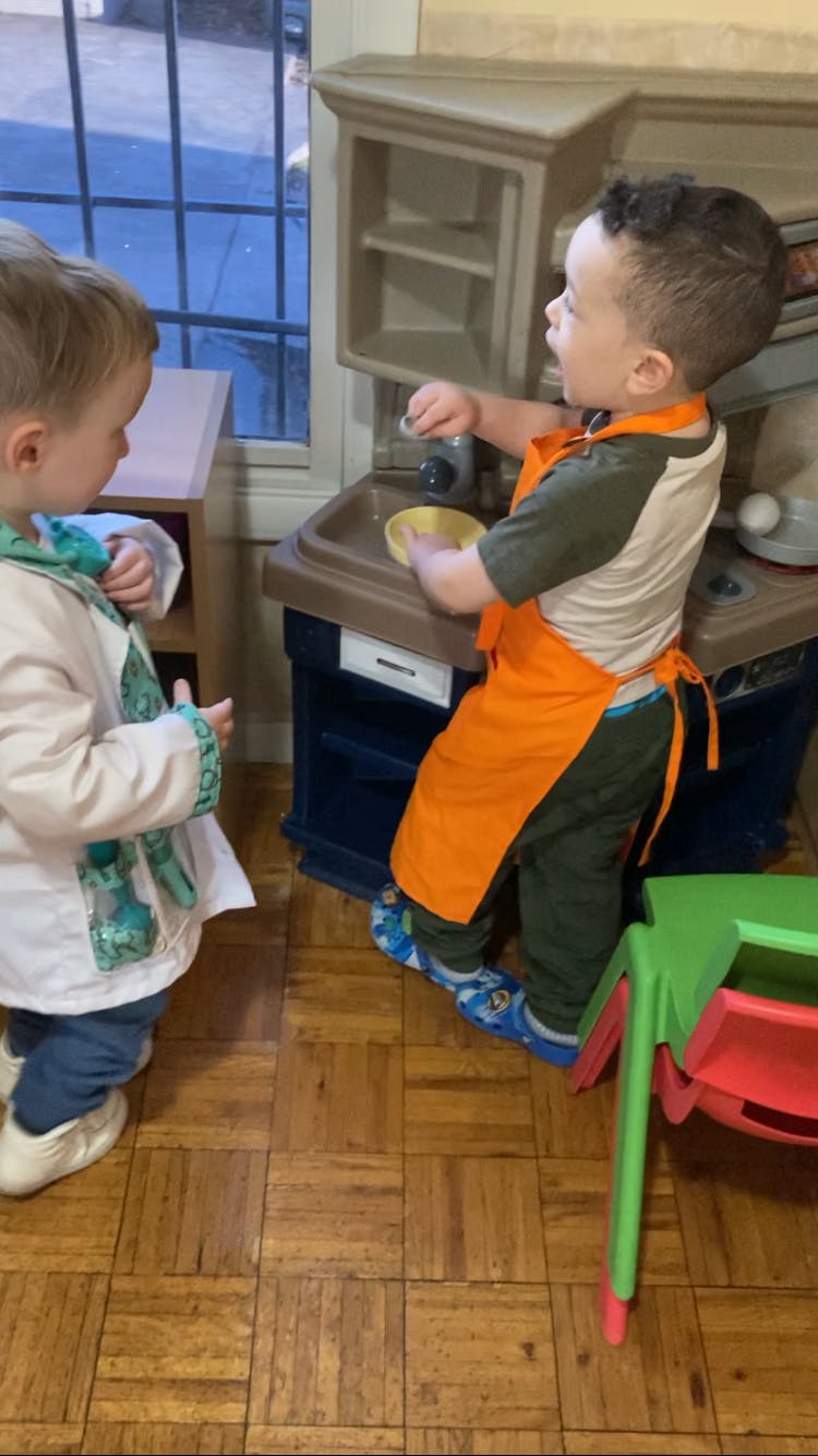 Two children playing with a toy kitchen set