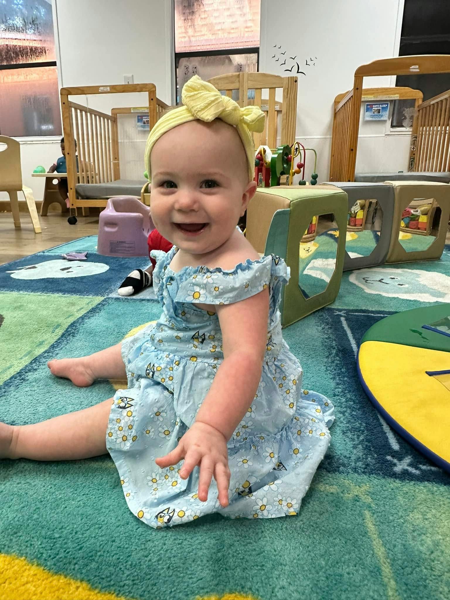 Child sitting on a rug in a room with cribs