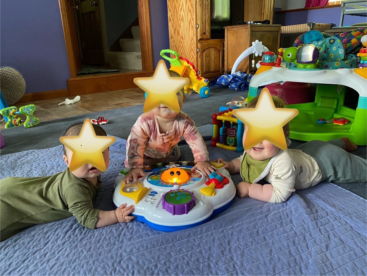 Three children playing with a toy on a blue mat