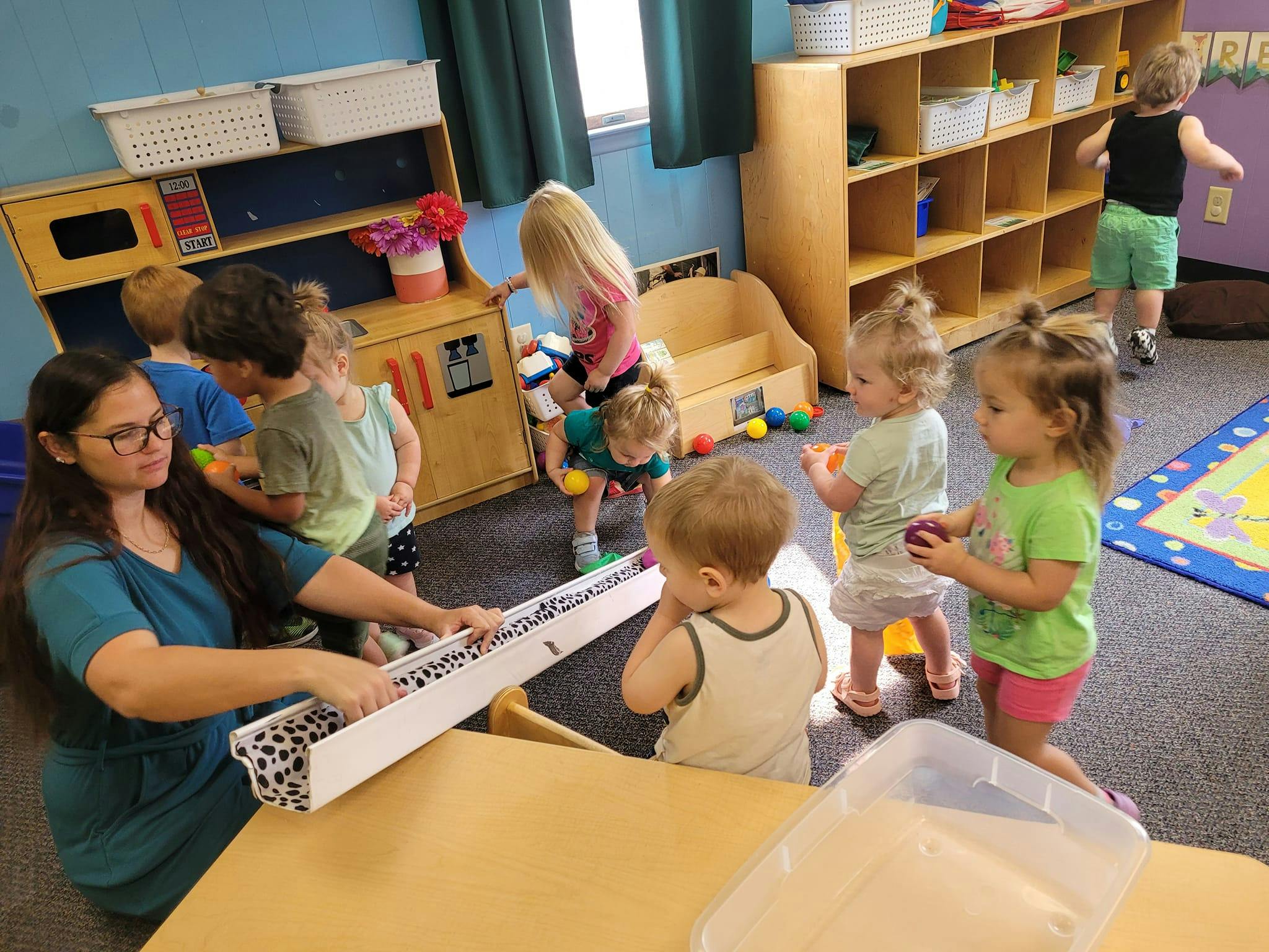 Adult and children playing with toys in a classroom
