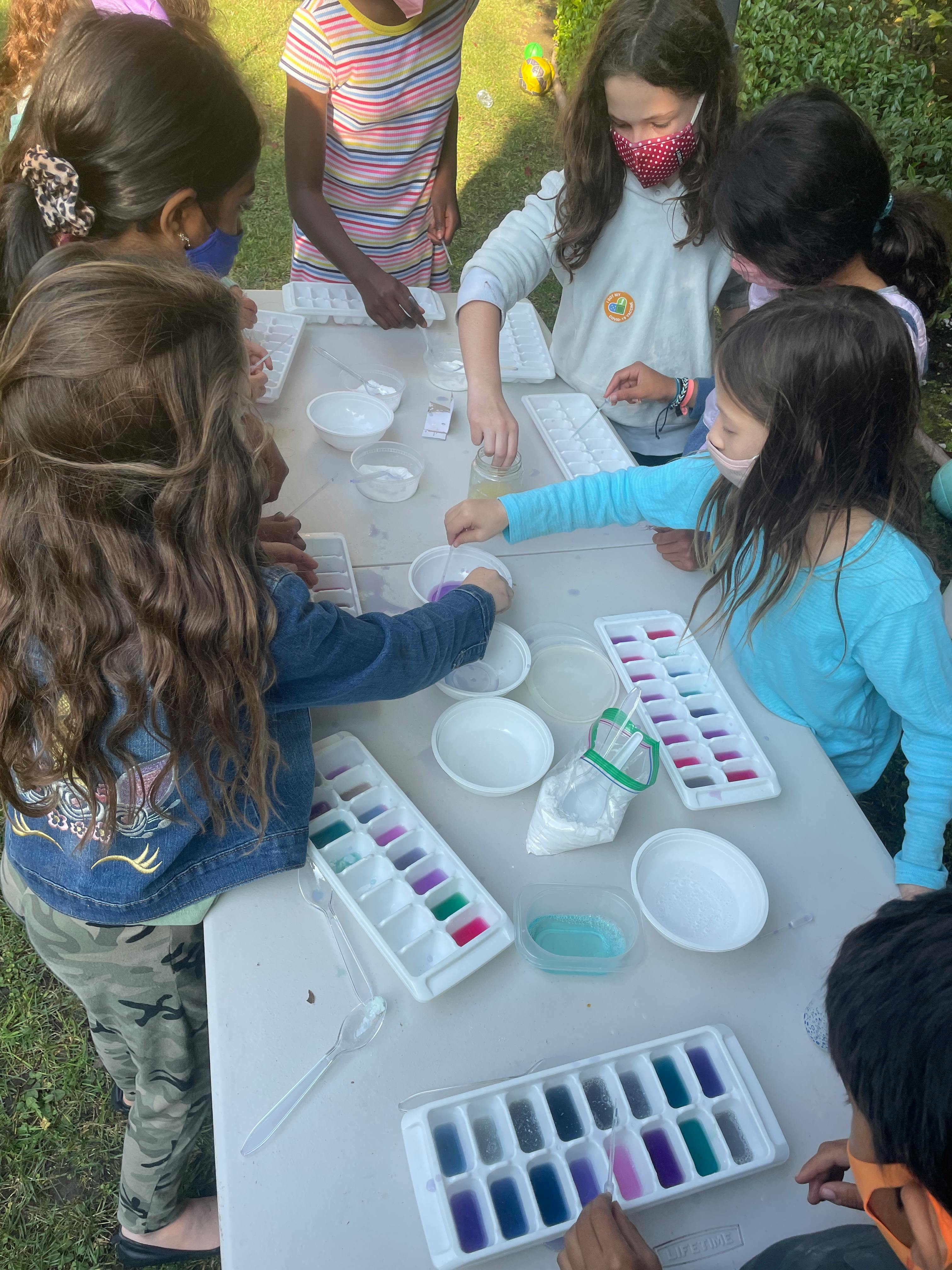 Children gathered around a table with ice cube trays and small bowls
