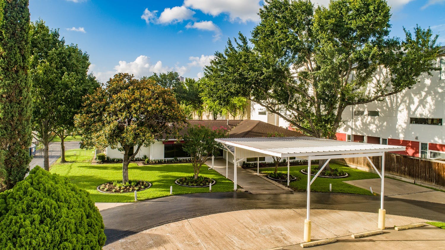 Carport with a building and trees in the background