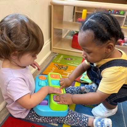 Two children playing with a colorful toy on a rug