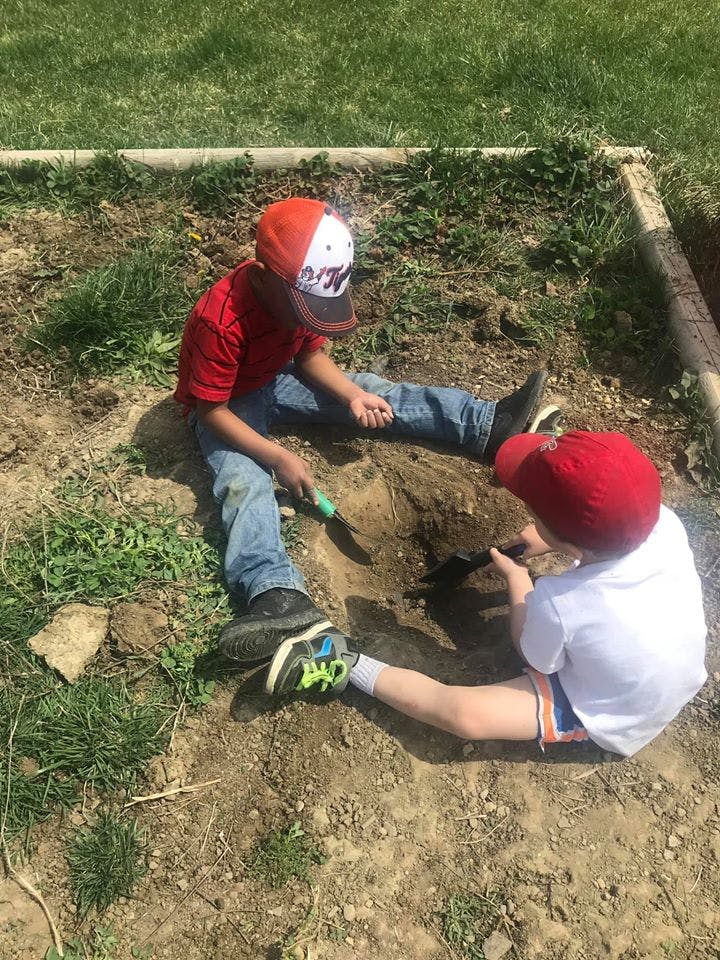 Two children digging in dirt with small shovels