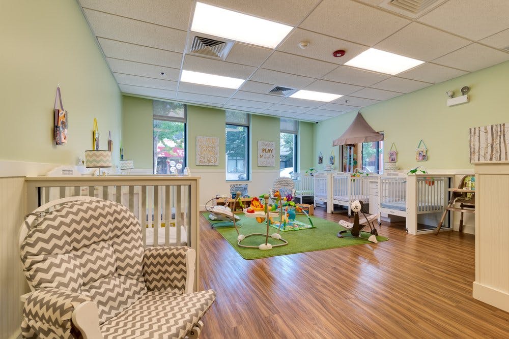 Nursery room with cribs, playmat, and rocking chair