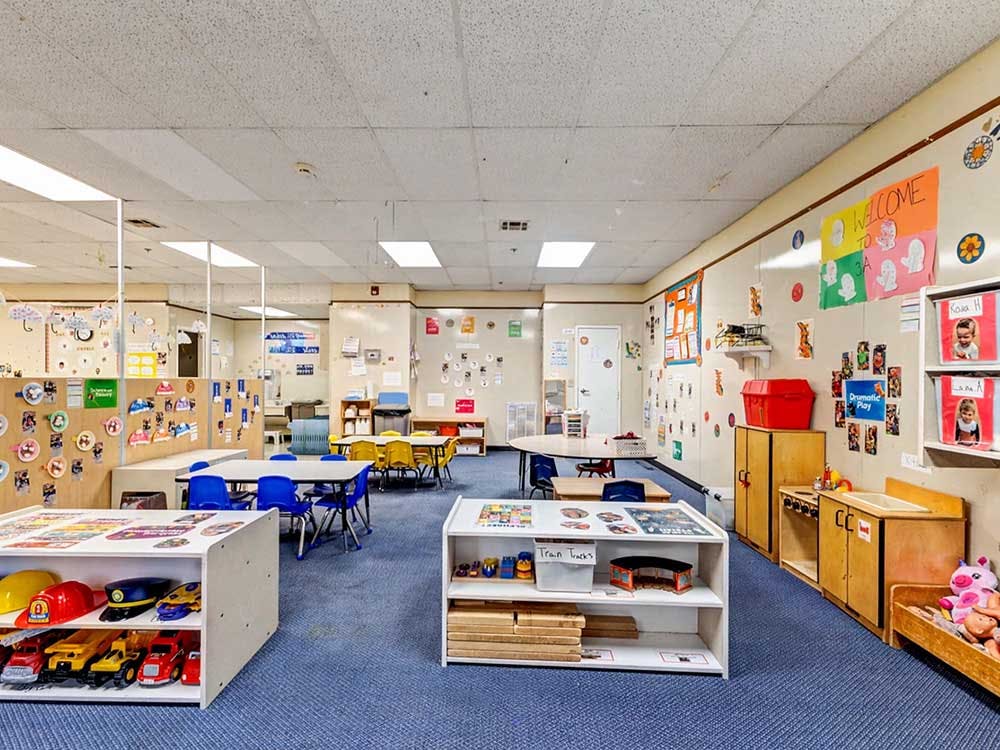 An empty daycare or preschool classroom with small tables and chairs