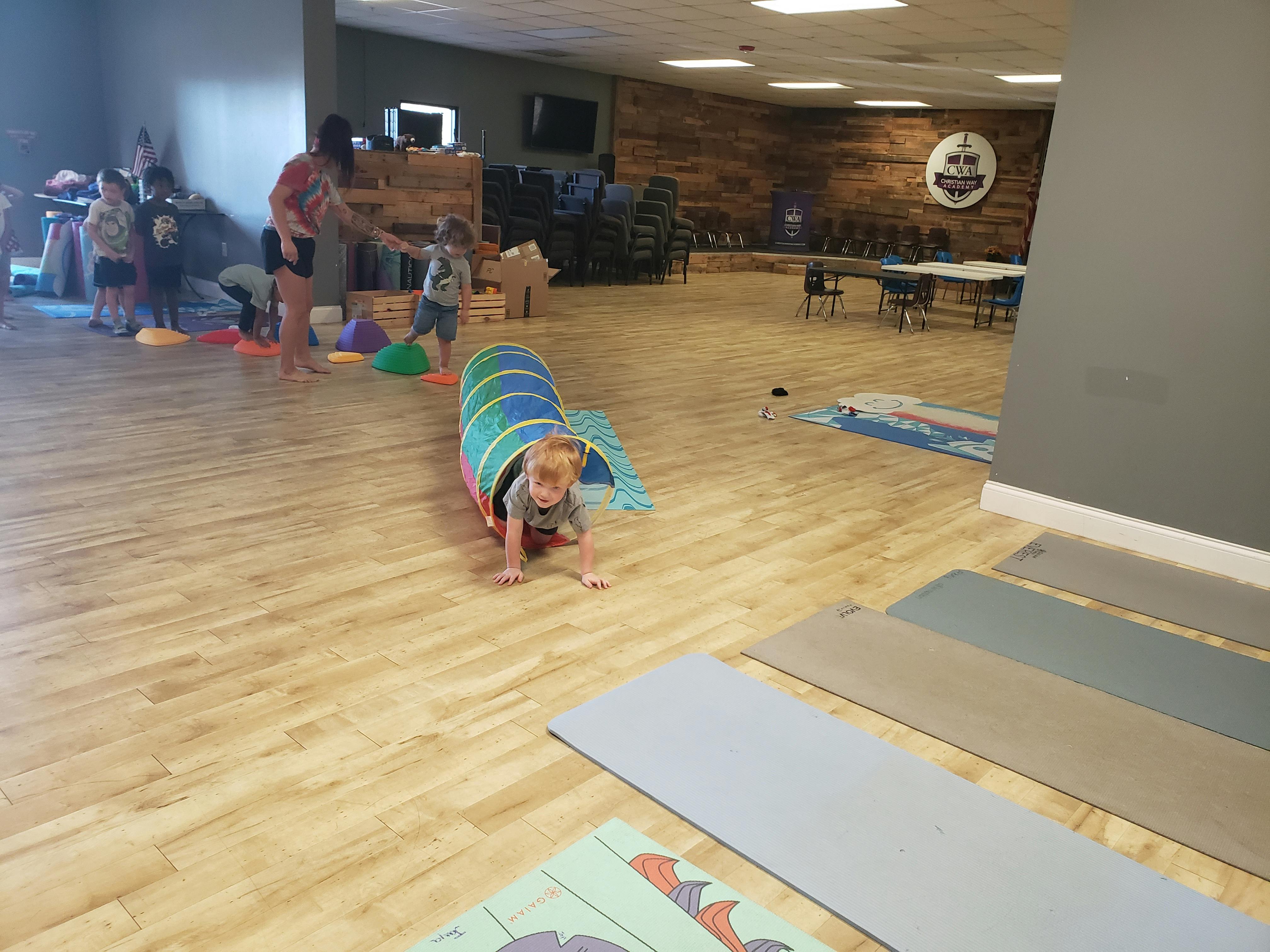 Child crawling out of a play tunnel on a wooden floor