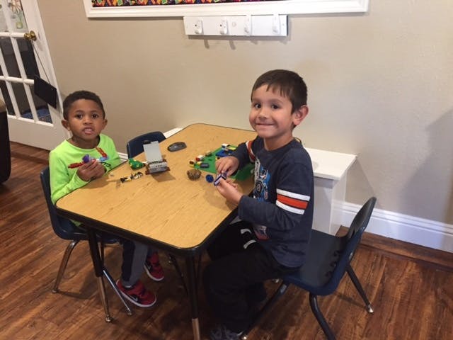 Two children sitting at a table playing with toys