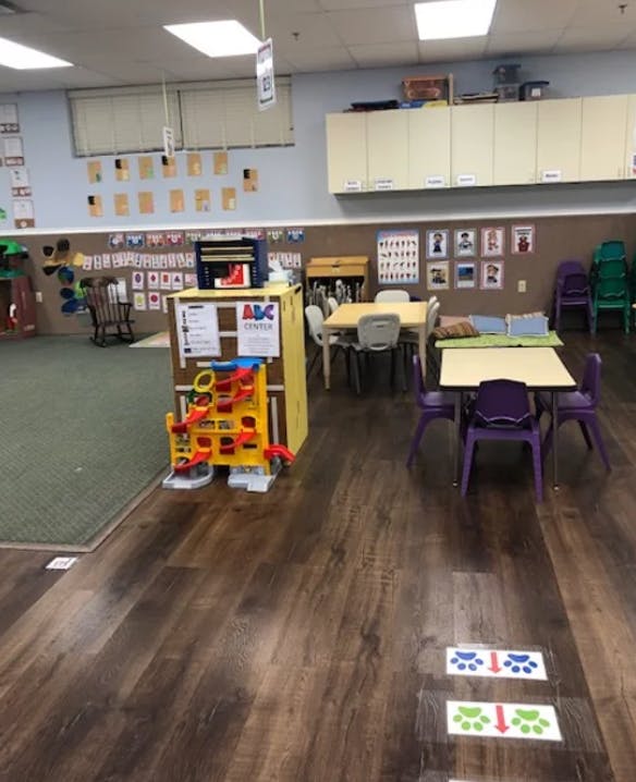 Classroom with small tables and chairs, and a play structure
