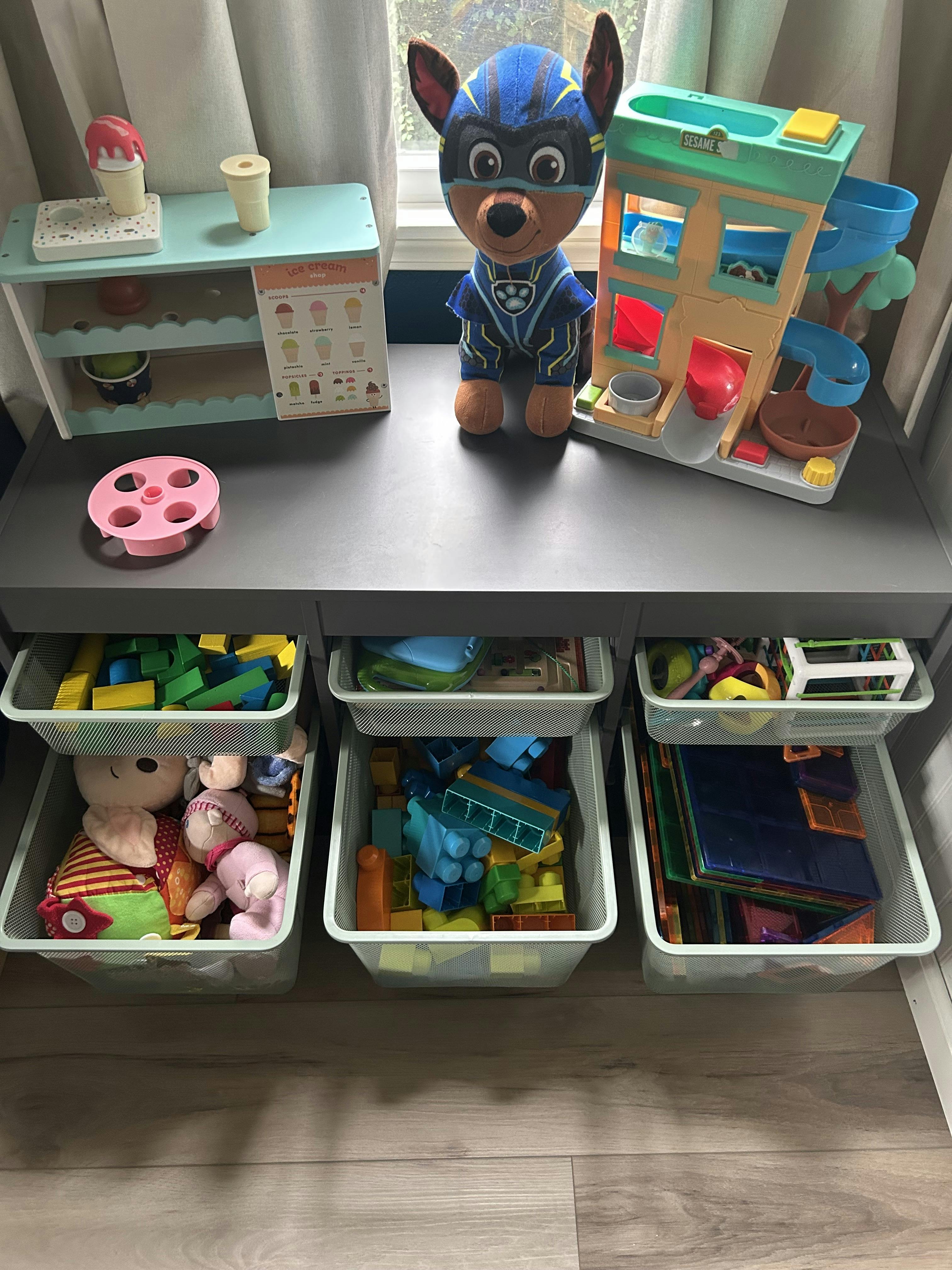 Children's toys on a table with storage bins underneath