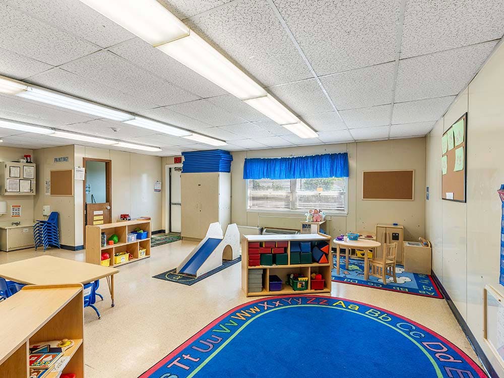 Empty colorful children's classroom with play equipment, tables, and chairs
