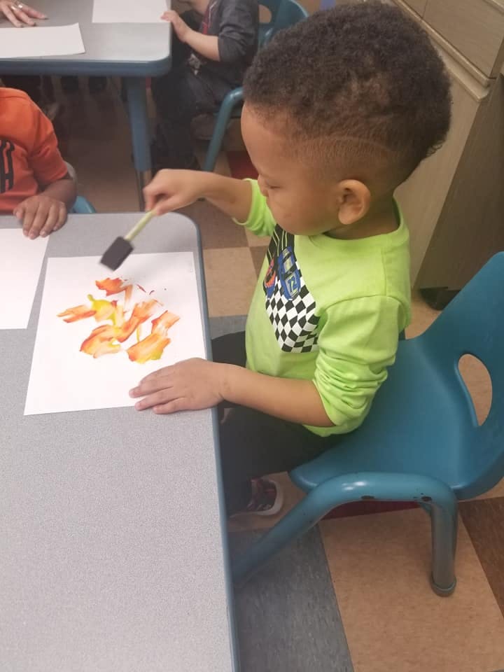Child painting on paper with a sponge brush