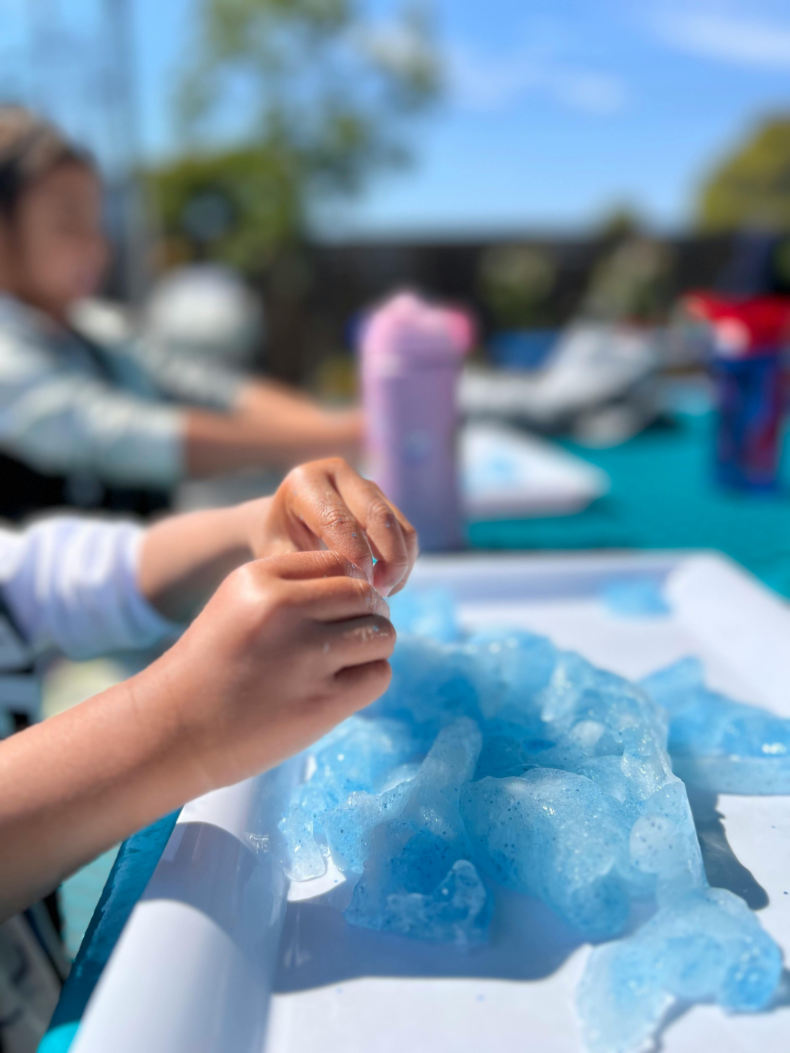 Child's hands playing with blue slime