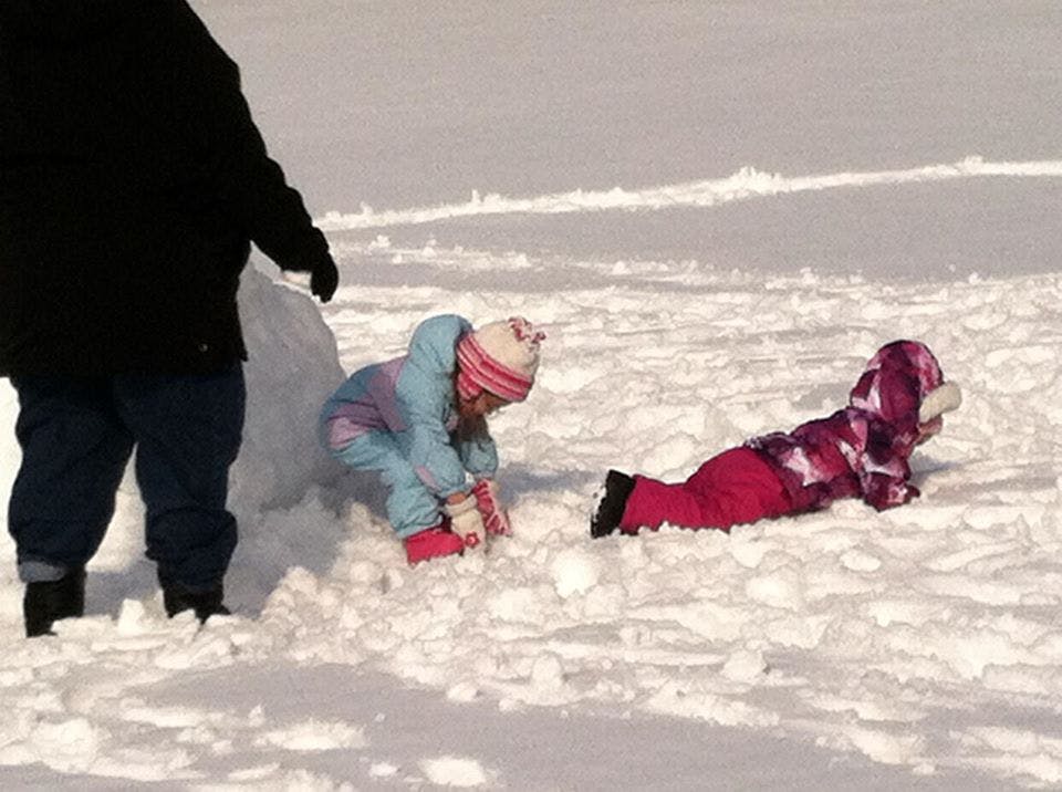 Person and two children playing in the snow