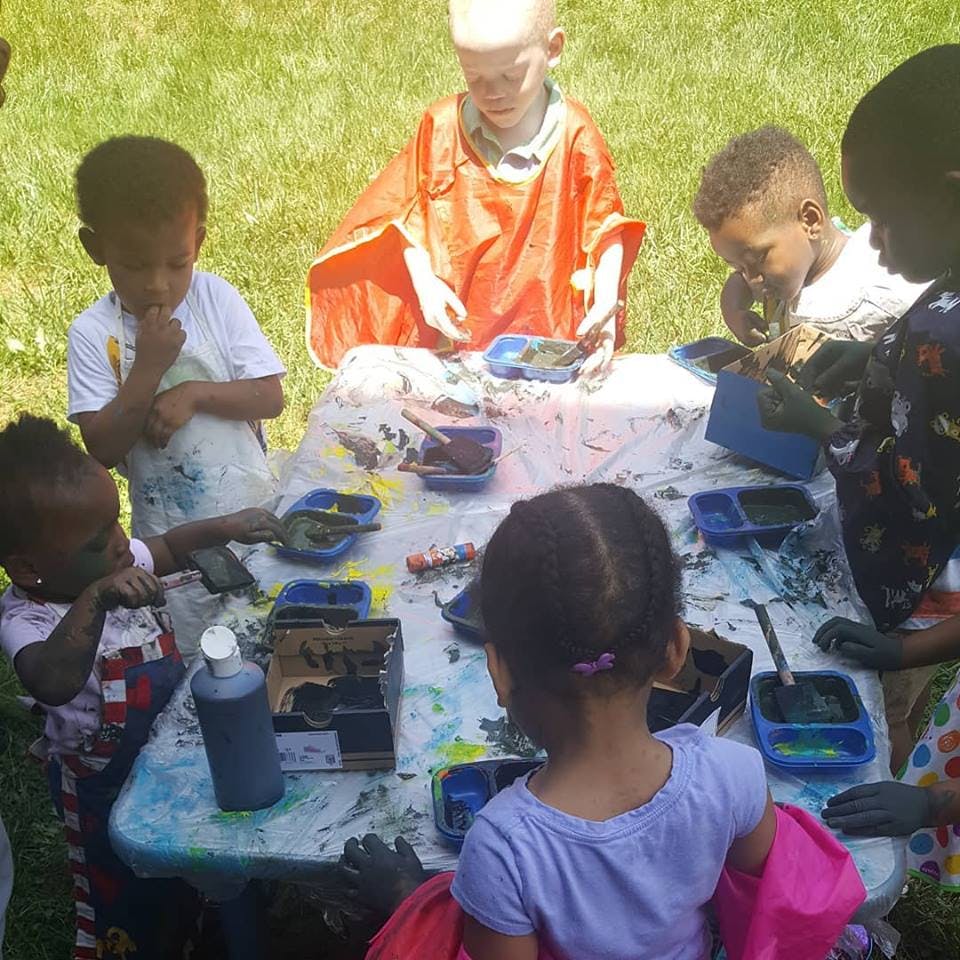 Children gathered around a table with paint and art supplies