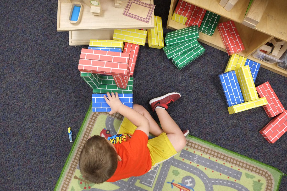 Child playing with colorful building blocks on a rug
