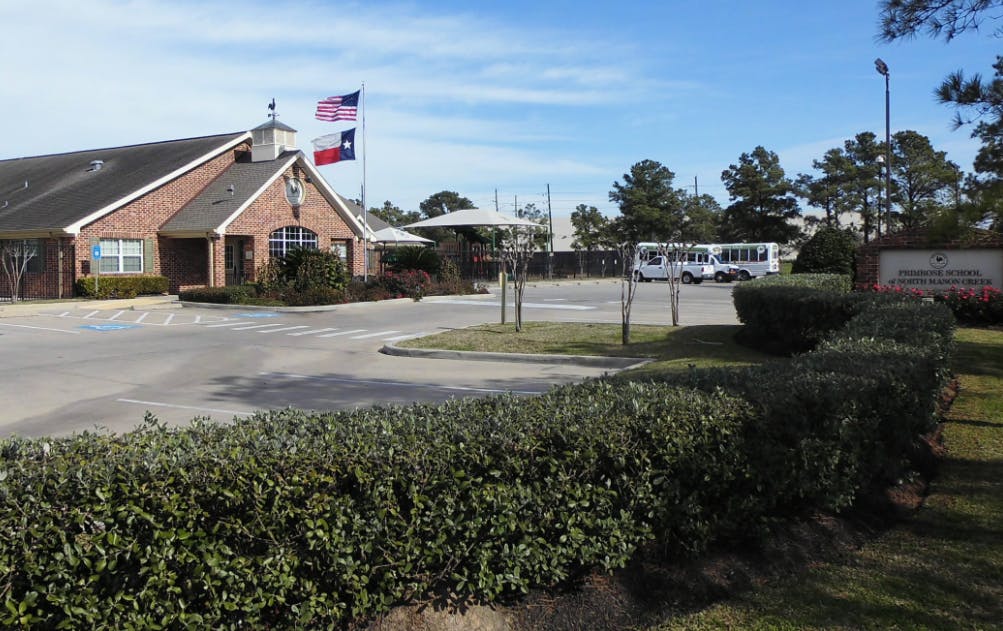 Brick building with flags flying and a bus in a parking lot
