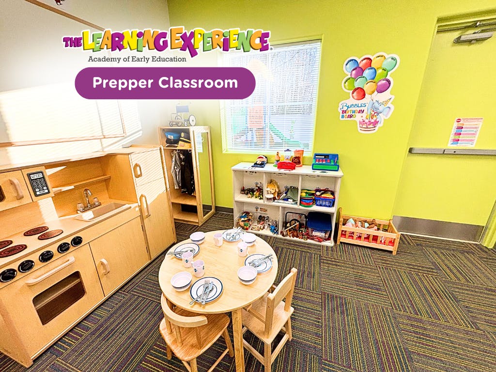 Play kitchen area in a classroom with a small table set with dishes