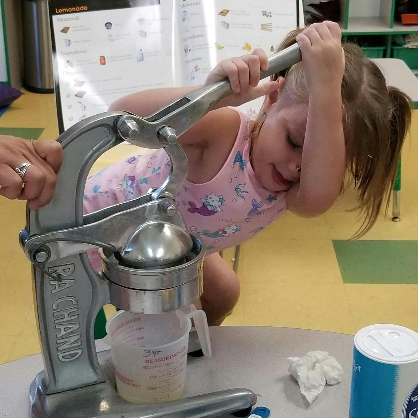 Child and person using a citrus juicer